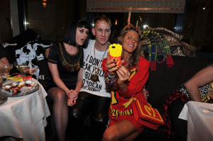 Jeremy Scott, creative director of Moschino, and Katy Perry sit for a selfie taken by Japanese Vogue editor-at-large Anna Dello Russo with her “Moschino fries”-covered phone. © SGP photo