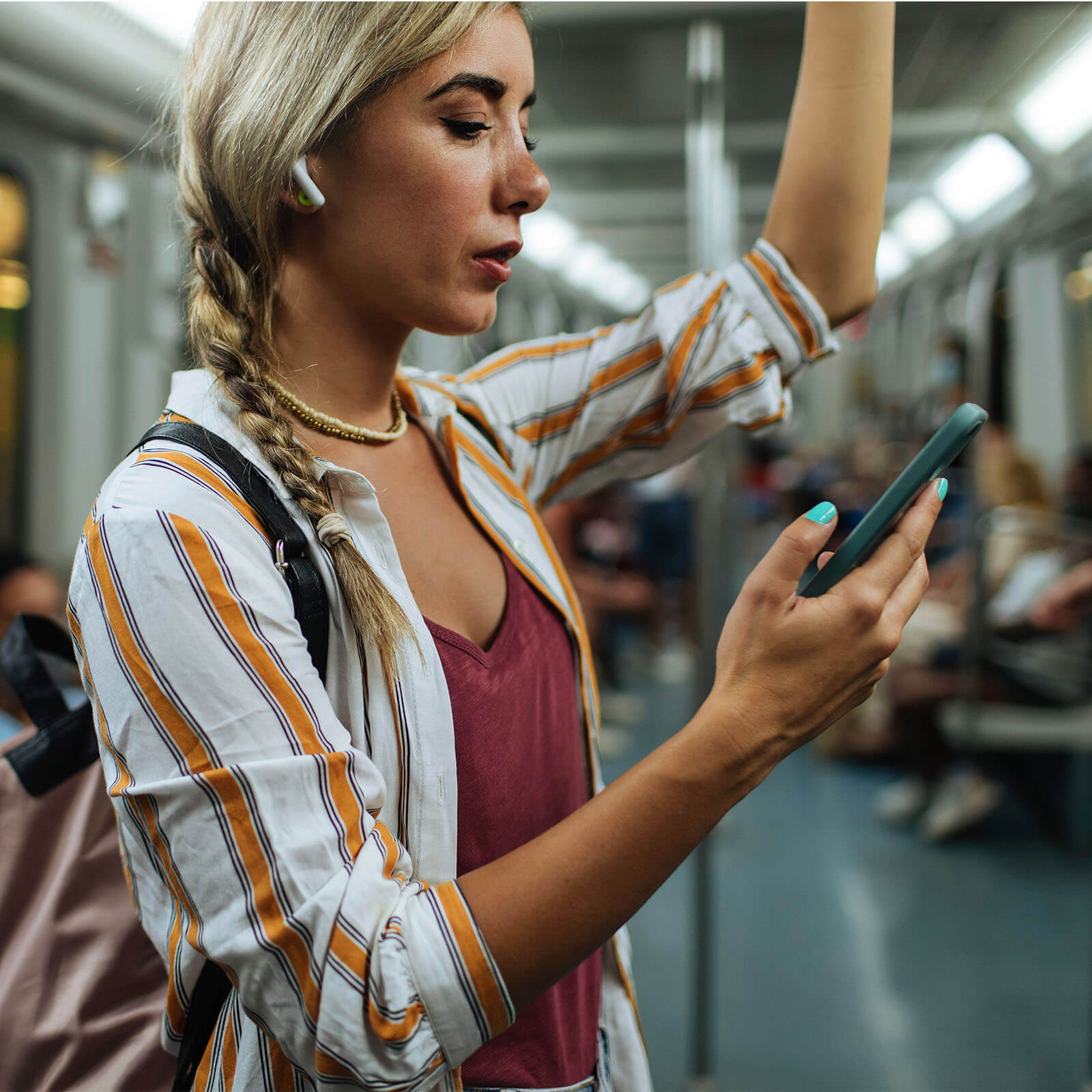 Rapariga no metro a ouvir música e a utilizar o telemóvel