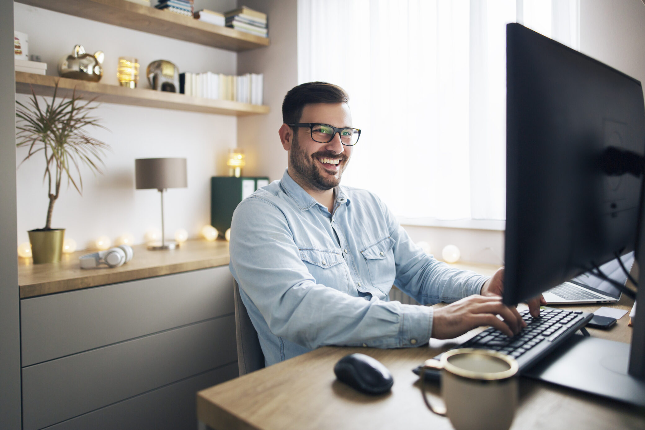 Homem em teletrabalho sorri em frente ao computador