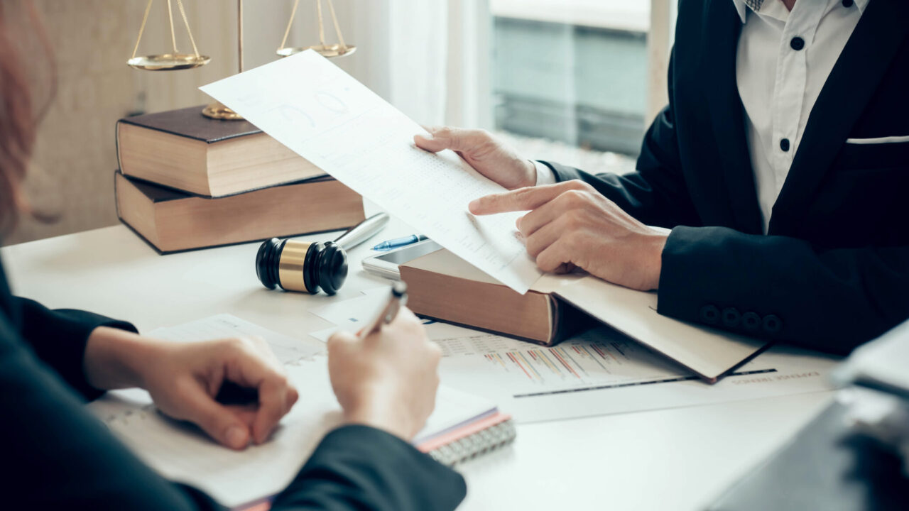 Duas pessoas analisam documentos legais sobre uma mesa, simbolizando a consulta e obtenção de registo criminal em Portugal.