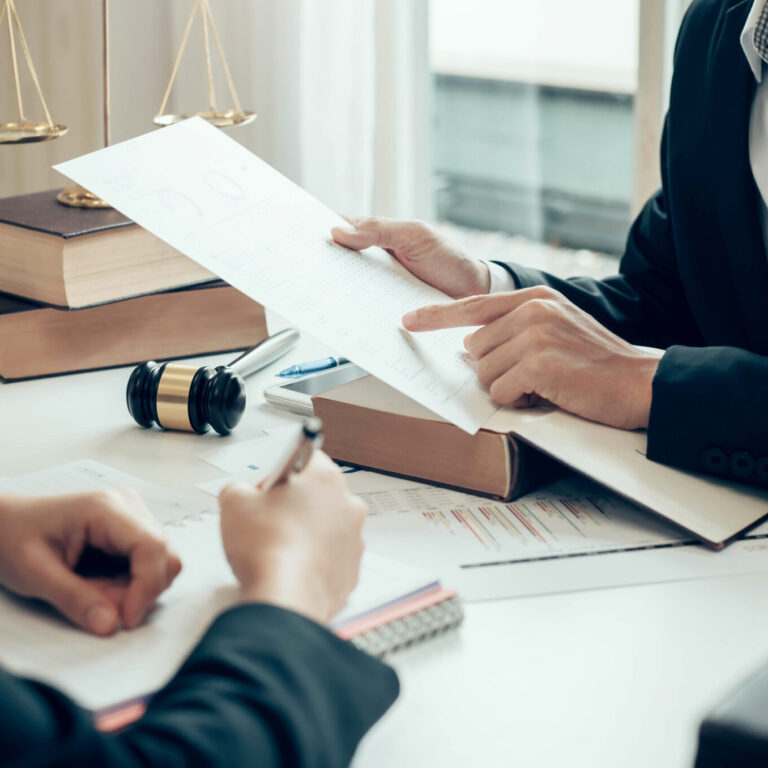 Duas pessoas analisam documentos legais sobre uma mesa, simbolizando a consulta e obtenção de registo criminal em Portugal.